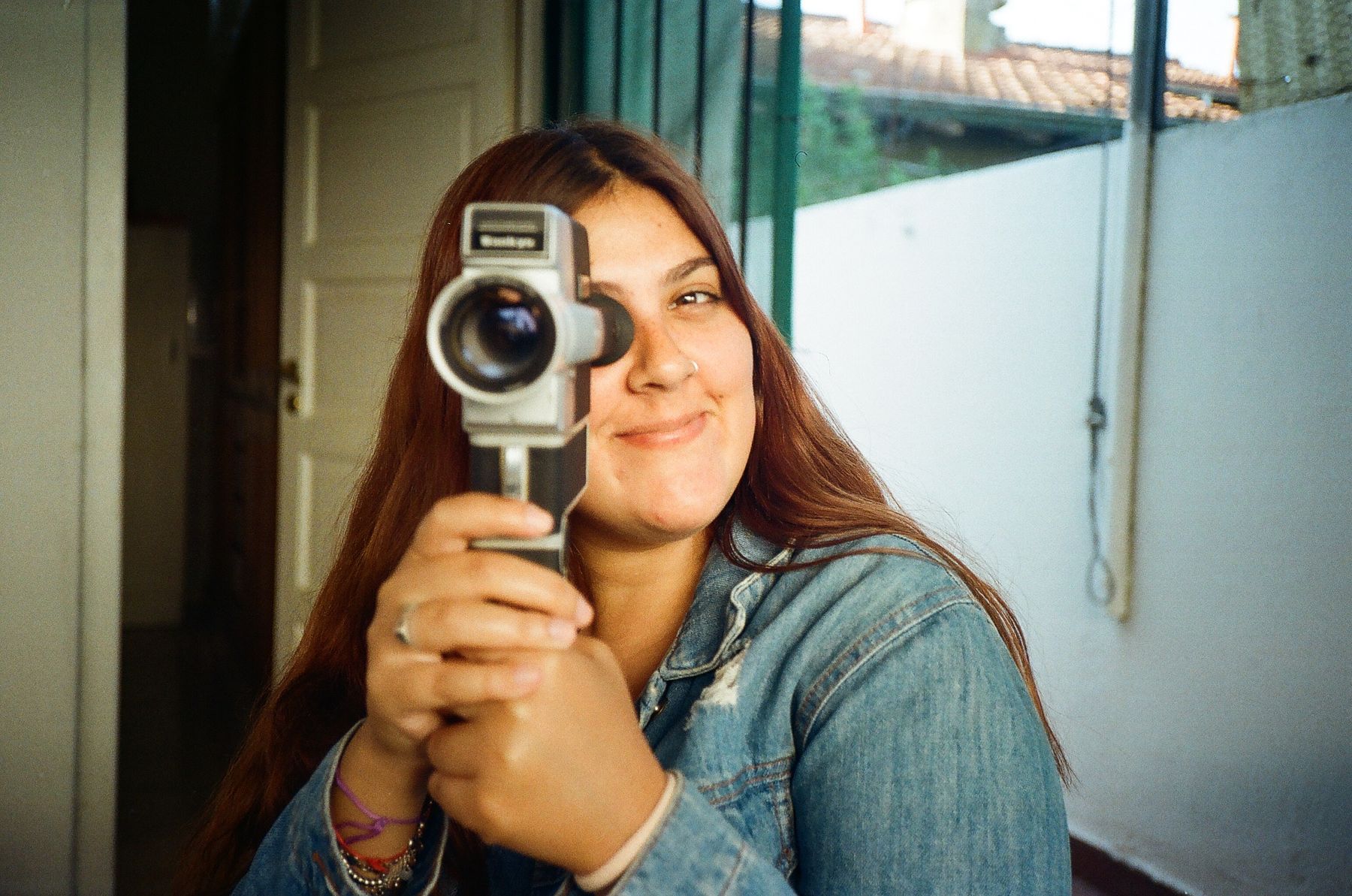 A smiling woman filming with a vintage camcorder